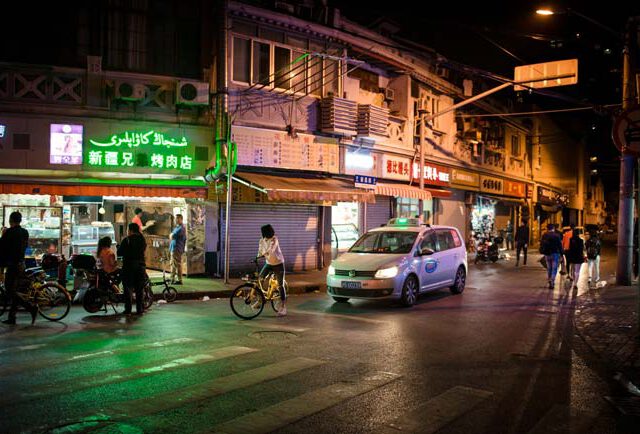 Nacht in Shanghai Strassenszene Taxi Fahrrad Leuchtreklame Streetphotography