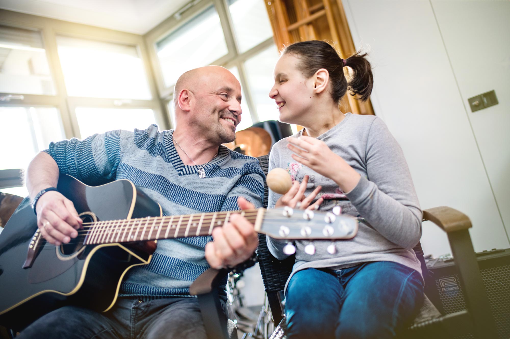 3-Nikolauspflege-Pflegedienst-Arbeit-mit-behinderten-Menschen-Musik-Mann-beim-Gitarrespielen-Lachen-Freude-Pfleger-Klient.jpg