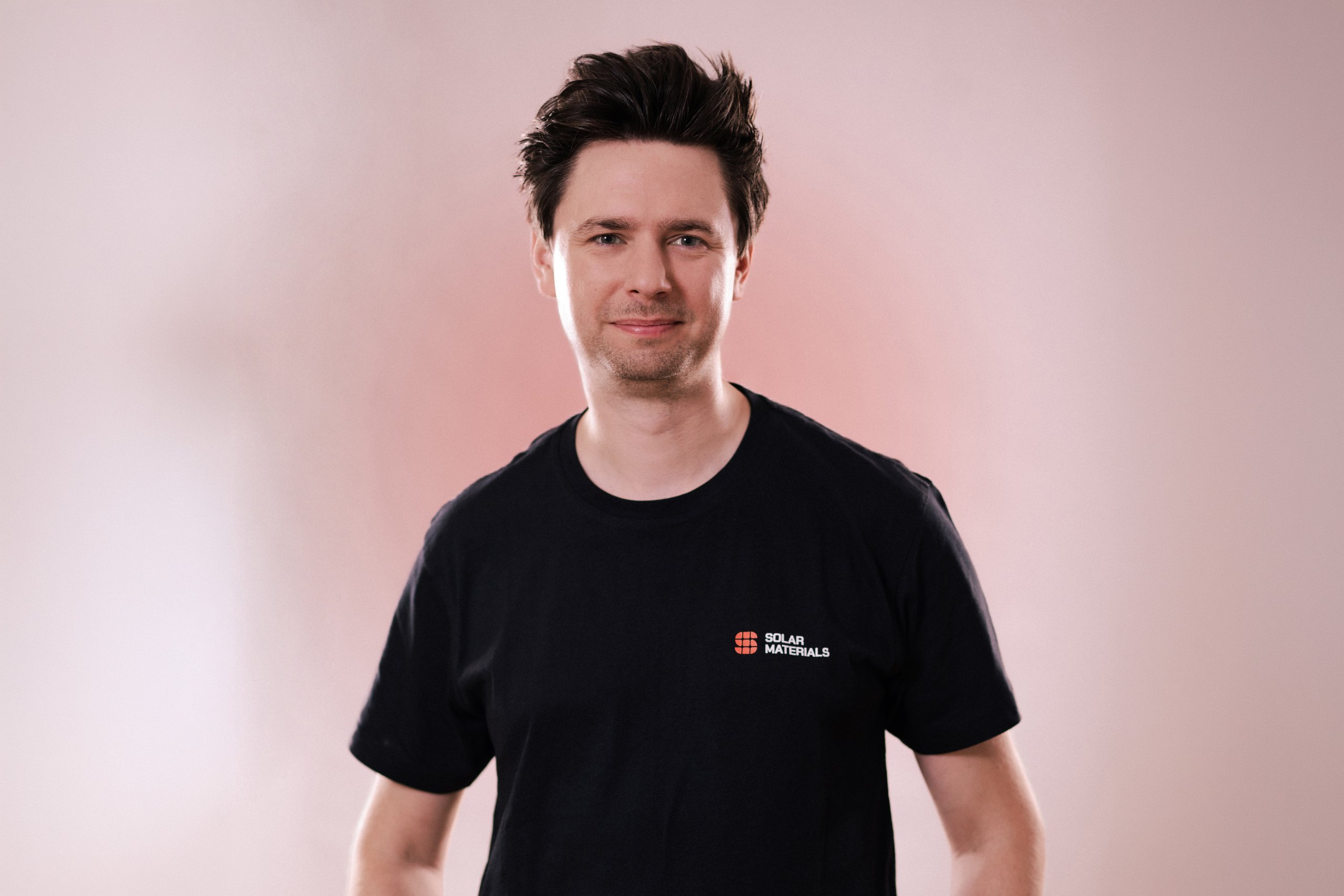 Mitarbeiterportraits Solar Materials Magdeburg – Mitarbeiter im Firmen-T-Shirt vor rosa Hintergrund, Solarmodul-Recycling